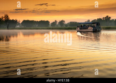 Seul bateau sur l'eau jaune billabong en lumière d'Aube dorée, Territoires du Nord, Australie Banque D'Images