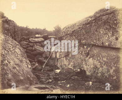 'Home of a Rebel Sharpshooter' d'Alexander Gardner est une célèbre photographie de la guerre de Sécession prise en 1863 à Gettysburg. Il représente un tireur d'élite confédéré allongé mort à côté d'un arbre, symbolisant les dures réalités de la guerre pendant la bataille de Gettysburg. La photographie de Gardner est remarquable pour son réalisme brutal et la documentation du coût humain de la guerre de Sécession. Banque D'Images