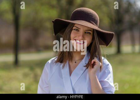 Portrait d'une jeune femme portant un chapeau dans un parc au printemps. Femme baissa la tête la tête vers la droite du châssis. Plan moyen. De faible profondeur Banque D'Images