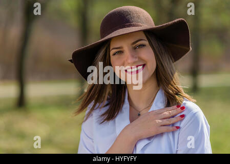 Portrait d'une jeune femme portant un chapeau dans un parc au printemps. Femme baissa la tête la tête vers la droite du châssis. Plan moyen. De faible profondeur Banque D'Images