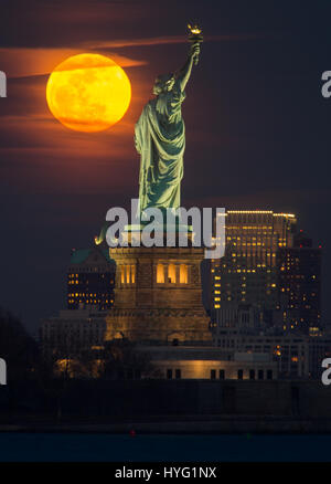 NEW YORK, USA : pris entre la lune et la ville de New York la statue de la liberté semble avoir son flambeau allumé avec une boule de lumière orange. Des images incroyables, montrer la pleine lune de sang de monter jusqu'à l'emblématique dame verte, illuminant la ville ci-dessous dans des tons orange. D'autres photos montrent l'Empire State Building est éclairé par l'arrière ce spectaculaire disque céleste. Rédacteur technique américaine Jennifer Khordi (46) a été en mesure de saisir ces photos à couper le souffle de l'horizon de Jersey City et Kearny ville dans le New Jersey. Banque D'Images