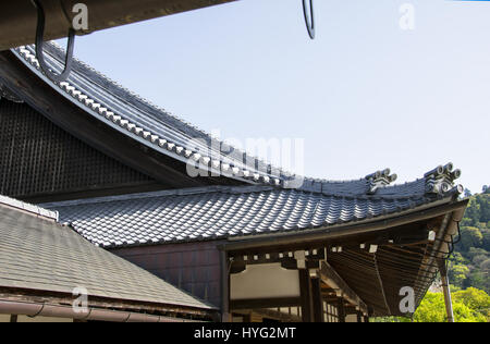 Détail sur le toit du temple japonais contre le ciel bleu pendant la saison des cerisiers en fleur. Banque D'Images
