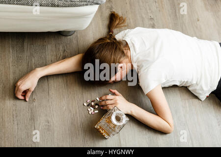 Ivre ou intoxiqué jeune femme avec bouteille d'alcool et des pilules, whisky et les drogues, la toxicomanie Banque D'Images