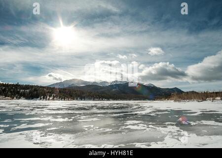 La solarisation de la lumière sur un lac gelé avec des montagnes dans le lointain. Banque D'Images