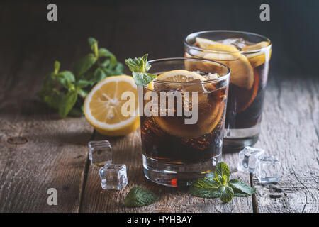 Cuba Libre frais avec rhum brun, cola, Menthe et citron sur fond de bois Banque D'Images