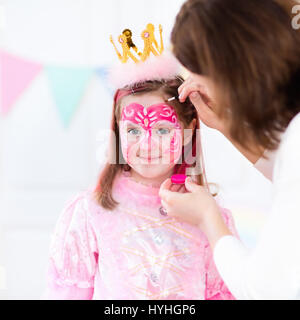 La peinture du visage de petite fille. Princesse et conte de thème d'anniversaire avec la peinture pour le visage de l'artiste et costume pour enfant d'âge préscolaire. Enfants célébrant Hallow Banque D'Images