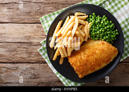 La cuisine britannique traditionnelle : fish and chips avec les pois verts close-up sur une plaque sur une table horizontale vue du dessus. Banque D'Images