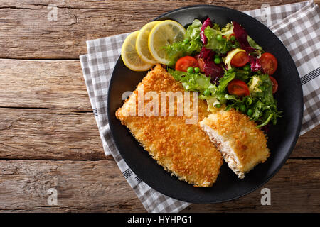 L'omble chevalier au plat filet de poisson dans la chapelure et salade de légumes frais sur une plaque horizontale vue du dessus. Banque D'Images