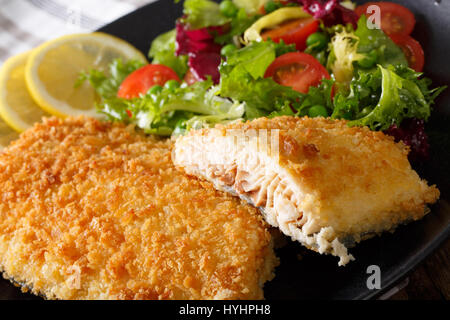 Filet de poisson de l'omble chevalier dans la chapelure et salade fraîche sur une plaque horizontale de macro. Banque D'Images