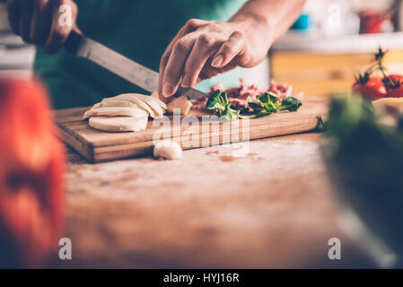 Woman slicing de mozzarella sur une planche à découper à la cuisine Banque D'Images