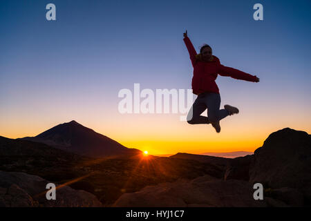 Jeune femme sautant en l'air, sur les roches, joie, Coucher de soleil, le volcan Teide et rétroéclairé, paysages volcaniques d'ossature Banque D'Images