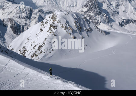 Le Skieur à la recherche sur la voie au champ de neige tout en décidant des choix de l'itinéraire en vallée dans les Alpes en hiver Banque D'Images