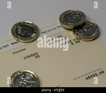 Déclaration de revenus personnels montrant les chiffres de l'impôt sur le revenu et d'impôt britannique couverts par quelques nouvelles pièces livre un Banque D'Images