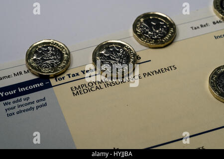Déclaration de revenus personnels montrant les chiffres de l'impôt sur le revenu et d'impôt britannique couverts par quelques nouvelles pièces livre un Banque D'Images