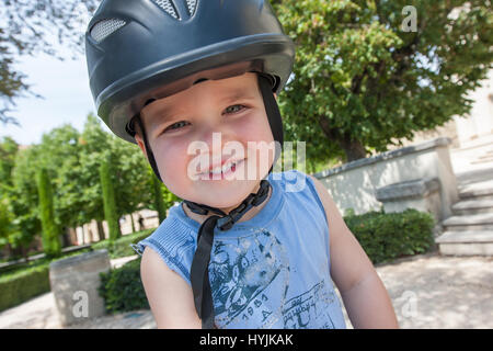 Un garçon portant un casque d'équitation est souriante Banque D'Images