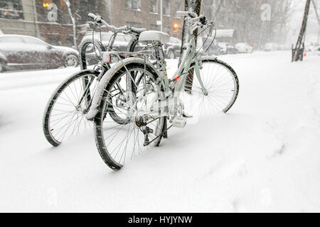 Deux bicyles enchaînés à un rack à l'extérieur sont couvertes de neige pendant une chute de neige à Manhattan. Banque D'Images