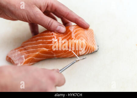 Chef, c'est la dépose de l'os de poissons saumon avec pince à épiler Banque D'Images