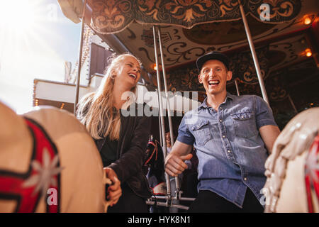 Smiling friends sur amusement park carousel. Jeune couple sur carousel ride. Banque D'Images