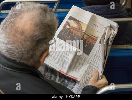 La lecture de l'homme dans l'article New York Times Journal sur bus, Manhattan, New York, USA Banque D'Images