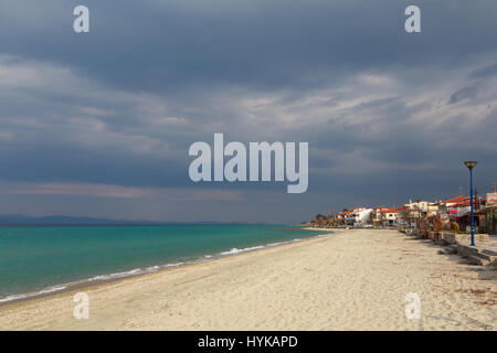 Le village sur le bord de la mer turquoise sous un ciel nuageux sombre avant que la pluie au coucher du soleil de la journée. Kassandra Halkidiki, Grèce Banque D'Images