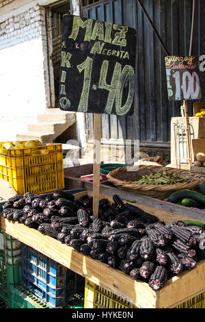 Le maïs violet foncé en vente sur un marché d'alimentation à Lima. Ce maïs est transformé en un jus épicé et sucré populaire appelé chica morada. Banque D'Images