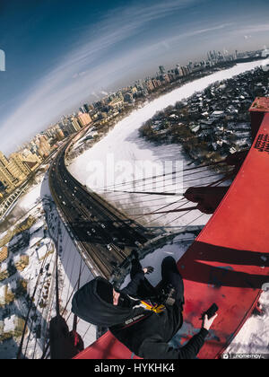 Moscou, Russie : regardez comme une excalibur monte le plus haut pont à haubans d'Europe et atteint le sommet à 344 mètres sans aucun équipement de sécurité. Les images et la vidéo montrent le grimpeur audacieux jusqu'dart les poutres en acier et les câbles avant d'atteindre un escalier ouvert et l'échelle. D'autres superbes clichés montrent l'Adrenaline Junkie triomphant posant en haut de la structure comme il est assis sur un rebord haut au-dessus de l'autoroute et des voitures qui passent au-dessous. Les images spectaculaires et des images ont été prises à Zhivopisnyy Bridge à Moscou, Russie par les photographe extrême et blogueur Alex Nomer Banque D'Images