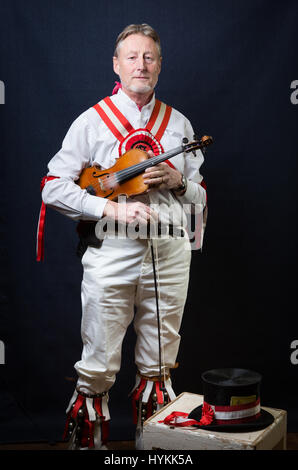 SURREY, UK : UNE Morris homme en costume traditionnel. Une célébration de la plus pure tradition de la danse Morris men a été révélé par un résident de Surrey sur la journée la plus importante de la tradition peut jour. Les images montrent les différents âges et les costumes de cette troupe de danseurs Morris dans portraits intimes. L'uniforme rouge et blanc avec des cloches et des rubans attachés ainsi que des hauts-de-forme, des bâtons, des accordéons et des violons accompagnent le groupe de danse. Filip photographe Jacek Gierlinski (39) a invité sa troupe locale de Morris men à un studio installé dans une église située sur Ewell, Surrey. Banque D'Images