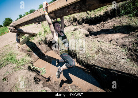 Au Wisconsin, USA : TOUGH MUDDERS sont représentés la lutte contre le fameux parcours extrême au nom de la charité et de l'esprit humain. La lutte contre leur chemin à travers le cours de dix milles composé de marécages boueux, de l'eau très froide, plonge, dix pieds de hautes clôtures et face à une course à travers 10 000 volts de rideau électrique, les images montrent comment ces coureurs prendre liens d'équipe à l'extrême. Les Villes Jumelles Tough Mudder événement a eu lieu à Hudson, Wisconsin et a vu 4 075 adrenaline junkies mettre leur corps par un travail sérieux. L'accent du cours est sur l'équipe et ne laissant aucun homme ou femme derrière. Banque D'Images