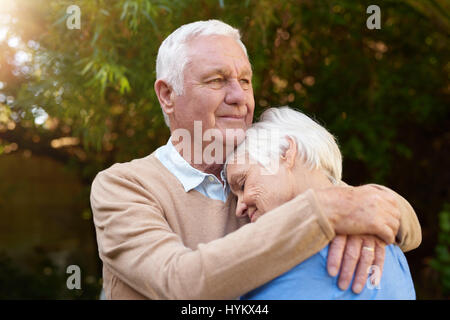 Smiling senior homme serrant affectueusement sa femme à l'extérieur Banque D'Images