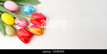 Tulipes rouges et peint les oeufs de Pâques sur table en bois Banque D'Images