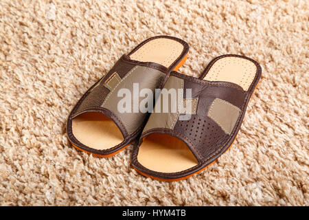 Chaussons en cuir pour hommes debout sur un tapis Banque D'Images