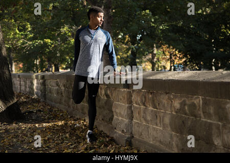 Un portrait d'un jeune homme qui s'étend alors qu'il se prépare à faire de l'exercice. Tourné au cours de l'automne 2016 à Prospect Park, Brooklyn, New York. Banque D'Images