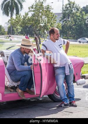 Les chauffeurs de taxi cubain dans leurs 50 ans classique rose voiture américaine, la vieille Havane, Cuba Banque D'Images