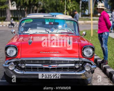 Portrait d'un chauffeur de taxi cubain élégant portant chemise rose debout à côté de sa voiture américaine classique rose correspondant, la vieille Havane, Cuba Banque D'Images