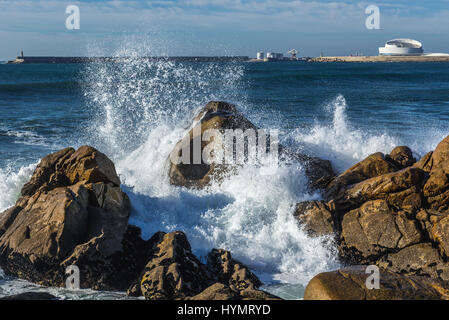 Smashing vagues contre des rochers sur la plage à Nevogilde paroisse civile de Porto, au Portugal. Port de Leixoes Cruise Terminal building on background Banque D'Images