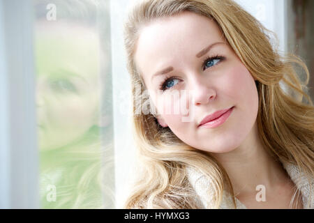 Close up portrait of a young woman gazing out window Banque D'Images