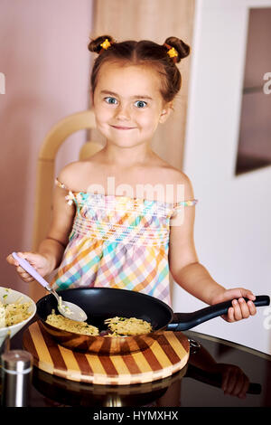 Cute little girl cooking crêpes de pomme de terre à la maison Banque D'Images