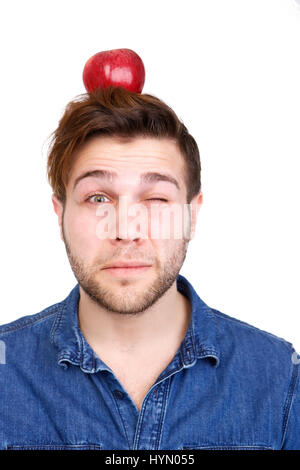 Portrait of a young man balancing red apple on head Banque D'Images