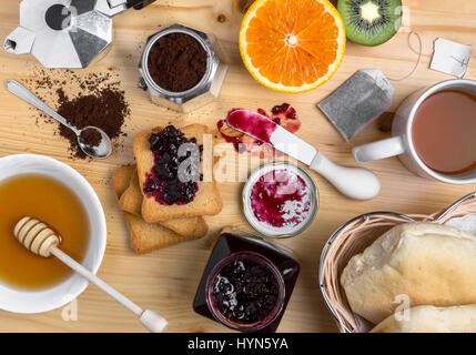 Table du petit déjeuner avec tasse de thé, confiture, fruits frais, pain, biscottes et de miel. Vue d'en haut. Banque D'Images