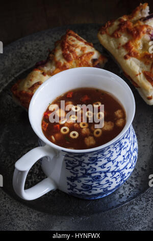 Une tasse de soupe minestrone avec de la mozzarella et oignons pain focaccia tourné à faible éclairage clés Banque D'Images