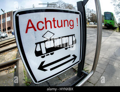 Un tramway s'approche d'un passage à niveau, où un signe avec le mot "Achtung" ("attention") met en garde les piétons à regarder des deux côtés avant de traverser les voies à Hanovre, Allemagne, le 31 mars 2017. Photo : afp/Hauke-Christian Dittrich Banque D'Images