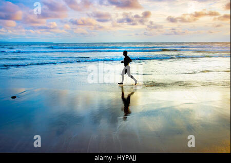 Homme qui court sur la plage au coucher du soleil. L'île de Bali, Indonésie Banque D'Images