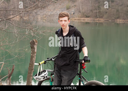 Young man on mountain bike se détend, sur fond de la mine inondée. Banque D'Images