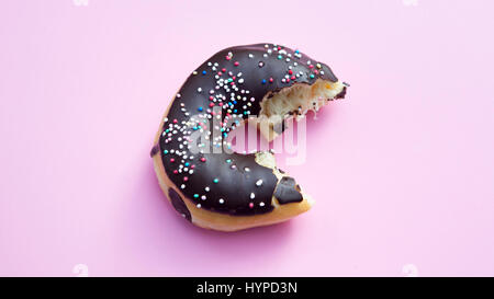 À moitié mangé donut avec garnitures colorées sur fond rose Banque D'Images