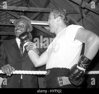 World Heavyweight Champion Sonny Liston (l) pose avec British heavyweight Billy Walker comme il plante un droit ludique sur sa mâchoire. Liston, payer une visite à la ferme, Essex, Pitsea où Walker a son camp d'entraînement, avait juste regardé le britannique de la formation. Banque D'Images