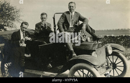 Meubles anciens 1915 photographie, trois hommes sur un roadster Ford automobile. L'immatriculation est de New York en 1915. Il y a un badge AAA sur la grille. Un homme est allumer une cigarette. SOURCE : tirage photographique original. Banque D'Images