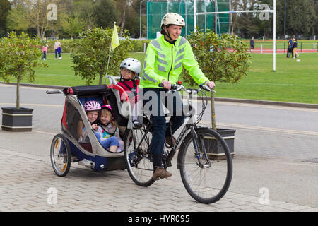 Cycliste femme sur Vélo / Vélo avec  + 3 enfants ; coopération avec siège enfant pilote casque & cycle remorquage remorque Chariot avec 2 / 2 enfants avec un casque. UK. Banque D'Images