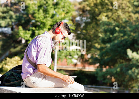 Lausanne, Suisse - le 26 août 2016 : Jeune homme dans les écouteurs lecture à l'Esplanade de Montbenon à Lausanne, Suisse. Banque D'Images