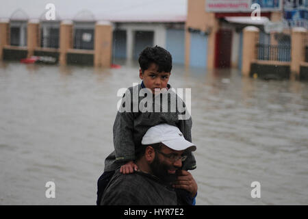 Srinagar, au Cachemire. Le 05 Avr, 2017. Cachemire homme porte son fils comme il fait son chemin dans une rue principale de Srinagar, gorgés d'la capitale d'été du Cachemire sur Avril 06, 2017 .La vallée a été le théâtre de fortes pluies depuis le mardi, menant à une nouvelle panique et des inondations, une augmentation soudaine du niveau de l'eau dans les rivières, ruisseaux et rigole en cachemire. Les autorités ont fermé tous les établissements d'Cachemire en raison de l'alerte aux crues éclair. Credit : Faisal Khan/Pacific Press/Alamy Live News Banque D'Images