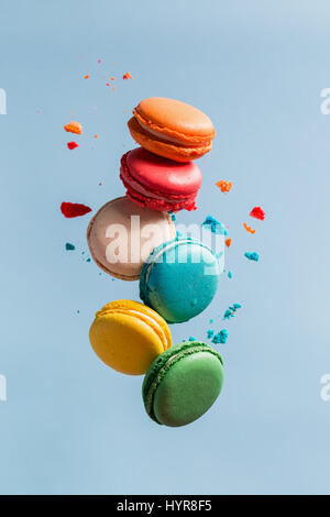 Différents types de macarons dans motion relevant sur fond bleu. Doux et coloré qui tombent ou qui volent les macarons français en mouvement. Banque D'Images